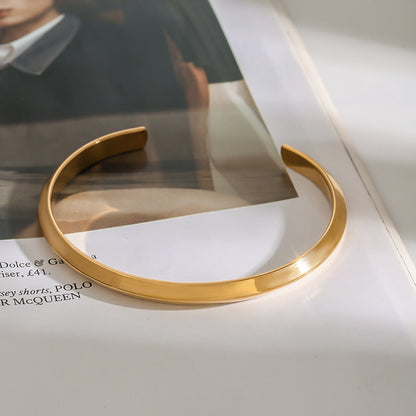 Gold bangle displayed on a fashion magazine page in soft daylight