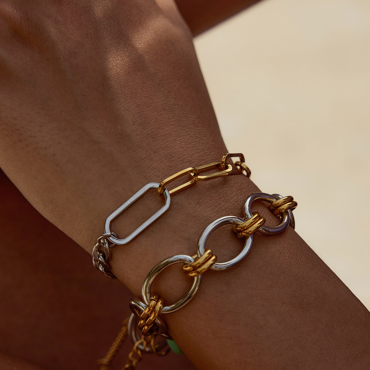 wrist shot showing two stacked bracelets including silver and gold chain link design