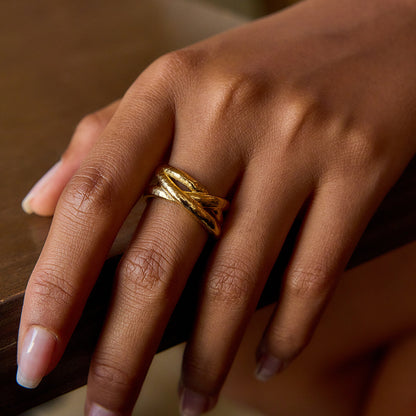 Hand wearing a gold ring with a blurred background