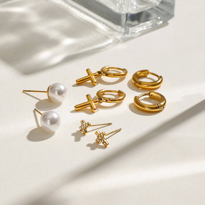 Minimalist gold huggie hoops with dangling cross, styled on ear