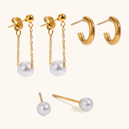 Studio close-up of gold hoop earrings, small pearl studs, and long chain pearl drop earrings