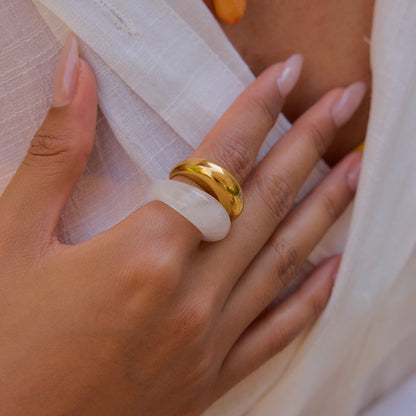 Transparent dome-shaped ring styled on model's hand with layered gold ring.