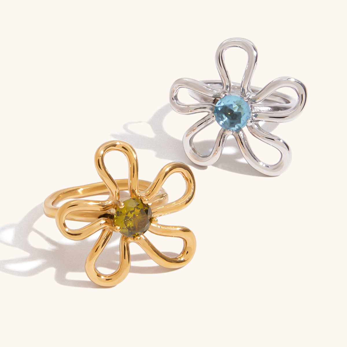 modern silver and gold flower rings with round-cut gems on white surface