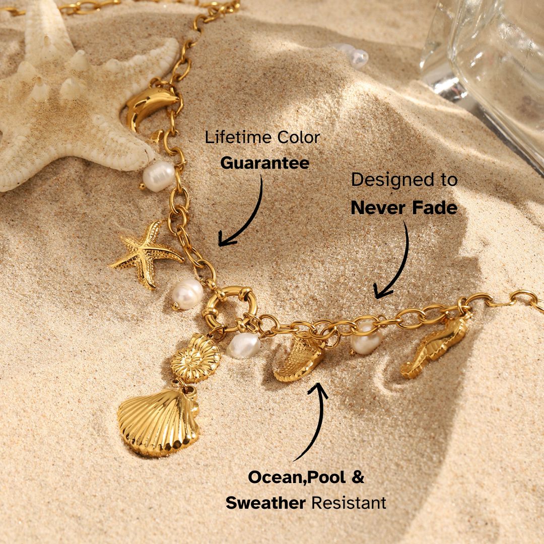 Gold starfish and shell charm necklace with pearls, styled on sandy beach backdrop