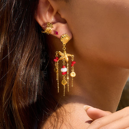 Close-up of beach-themed shell earrings with long gold chains