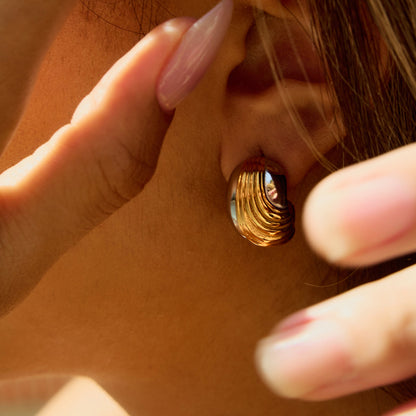 Woman adjusting chunky gold silver earrings with manicure detail