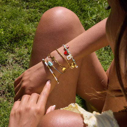 Stackable beach-style bracelets with evil eye and red bow charms