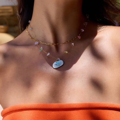 Pastel gemstone necklace with colorful fish pendant on model’s neck under sunlight