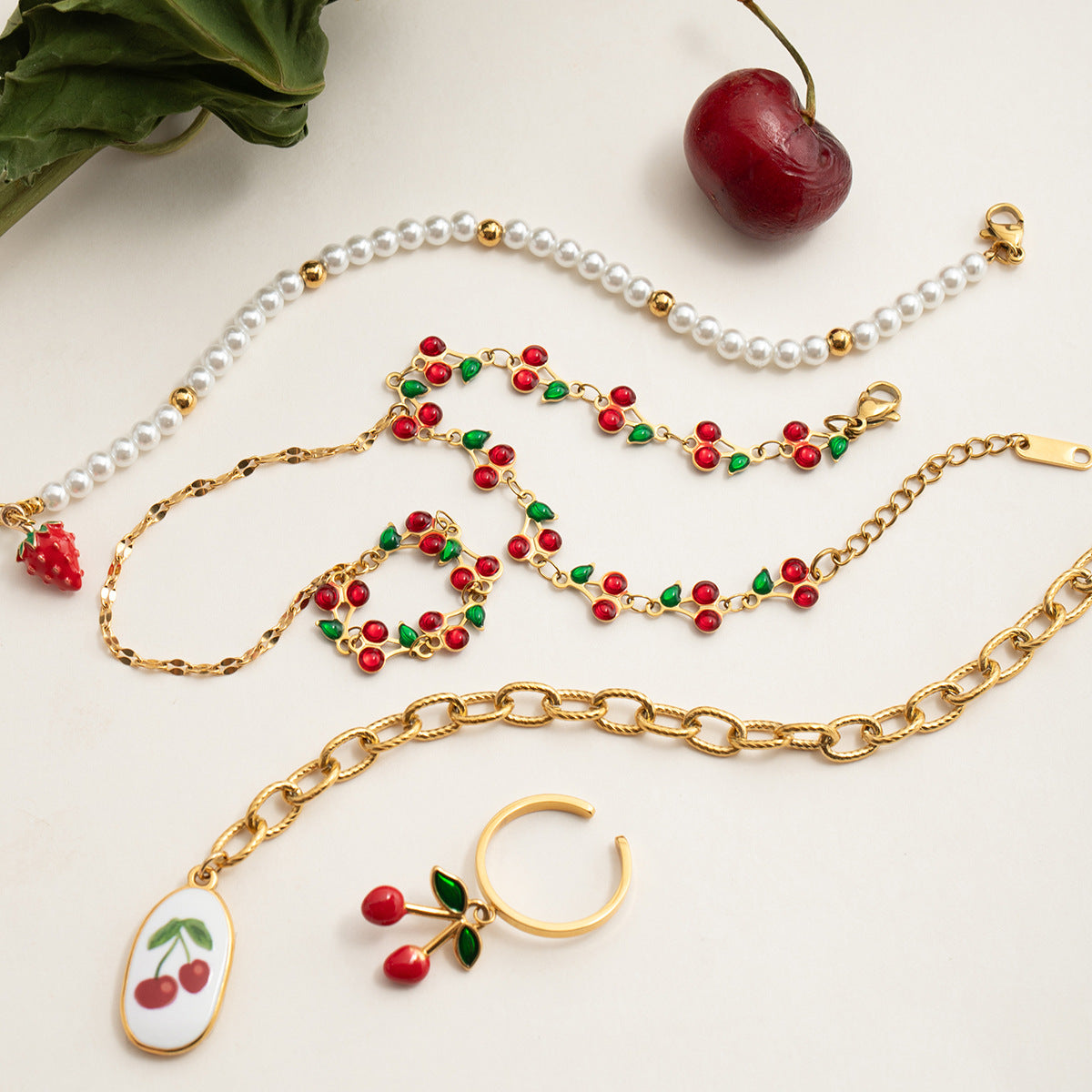 Playful cherry chain bracelets and matching accessories styled with pearls and gold links