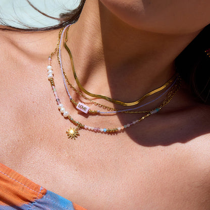 Close-up of waterproof pearl and sun charm necklace on skin