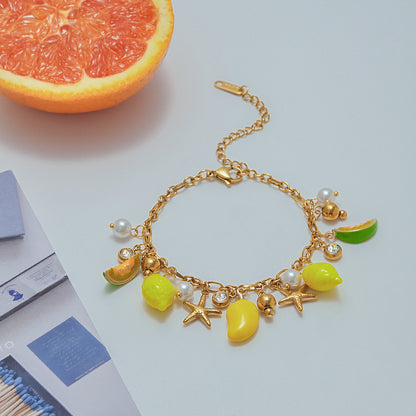 Close-up of summer fruit bracelet with pearls and gold charms next to grapefruit
