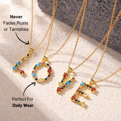 'LOVE' pendant necklace with colorful zircon stones in red, blue, green, and yellow, on a golden chain with a light stone background.