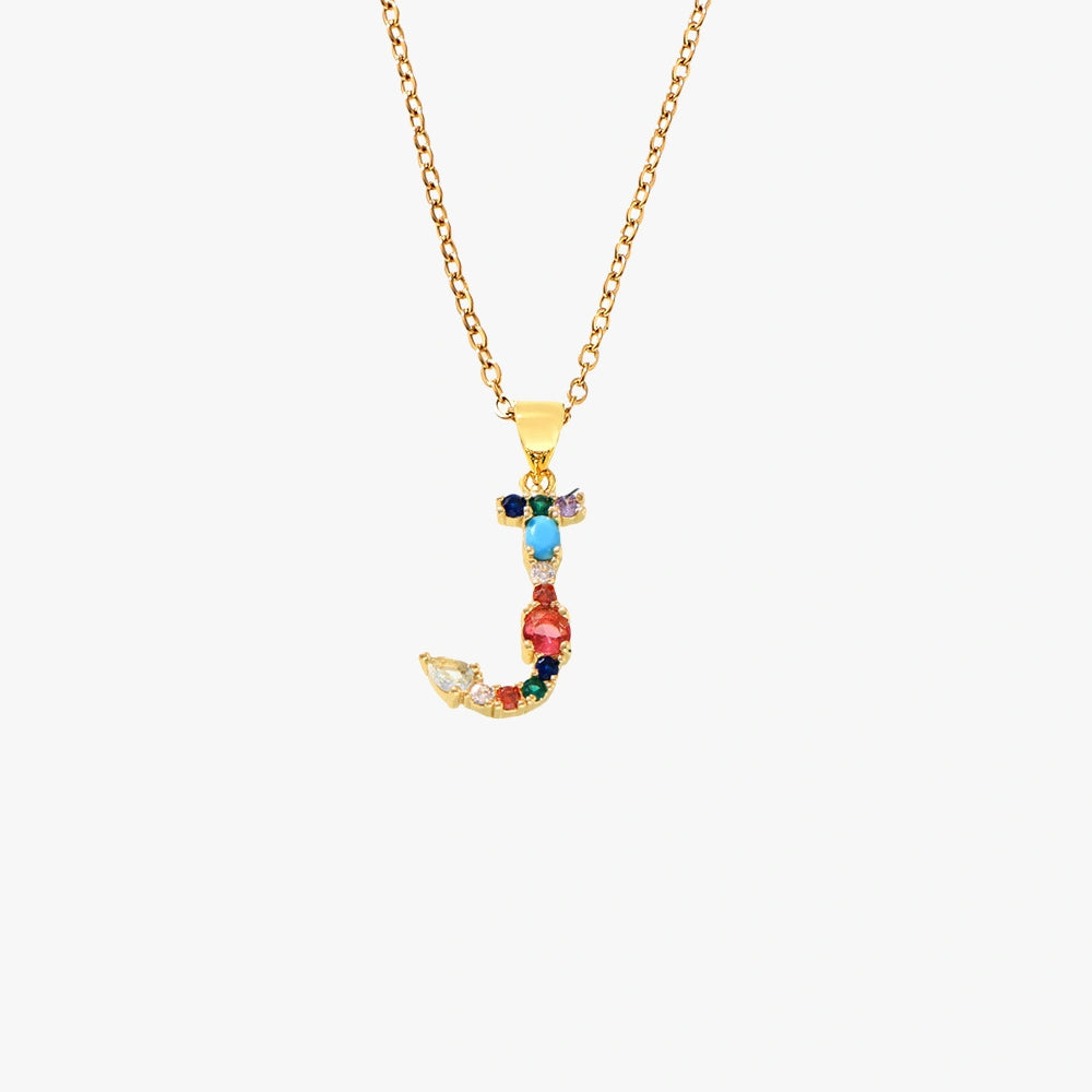 Gold letter J pendant with colorful zircon stones in red, blue, and yellow, suspended from a chain.