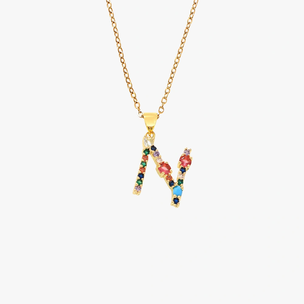 Letter N pendant in gold featuring colorful zircon stones in red, blue, and green, hanging from a gold chain.
