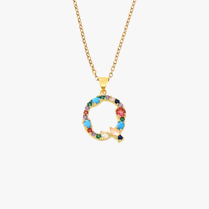 Golden pendant in the shape of the letter Q, adorned with vibrant zircon stones in red, blue, and yellow on a delicate chain.
