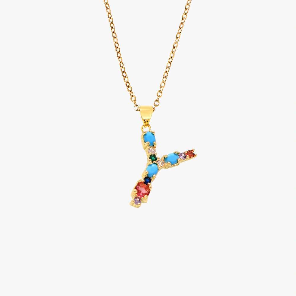 Golden letter Y pendant with colorful zircon stones in red, green, and blue, hanging from a gold chain.