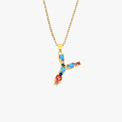 Golden letter Y pendant with colorful zircon stones in red, green, and blue, hanging from a gold chain.