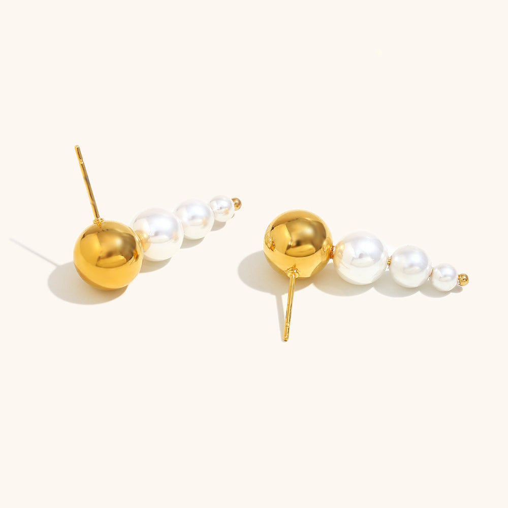 Close-up of overlapping modern gold and pearl earrings on a light background, fashion jewelry style.