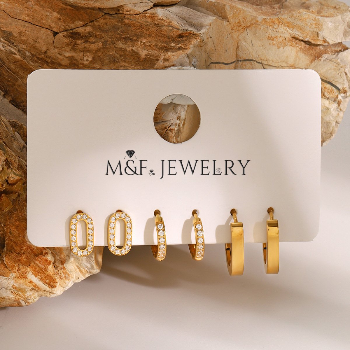 Small gold hoop earrings encrusted with crystals, displayed on stone background