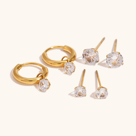 Gold hoop earrings and stud set with sparkling zirconia stones styled on beige background