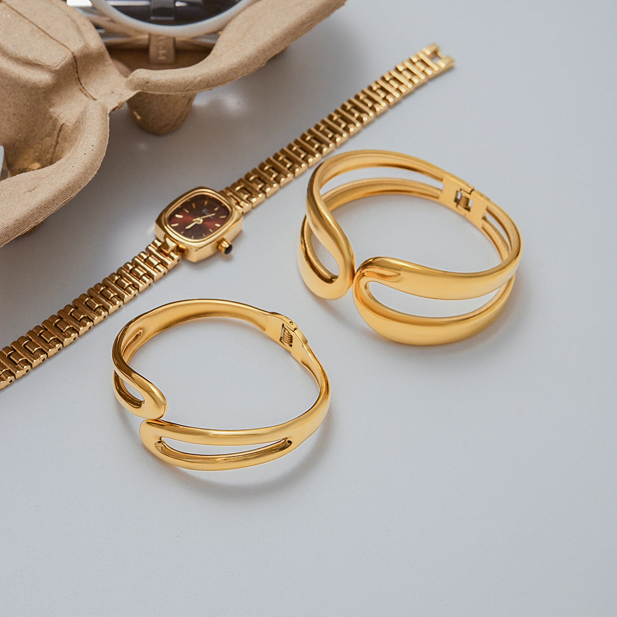 Abstract curved gold bracelets styled with retro watch and sunglasses