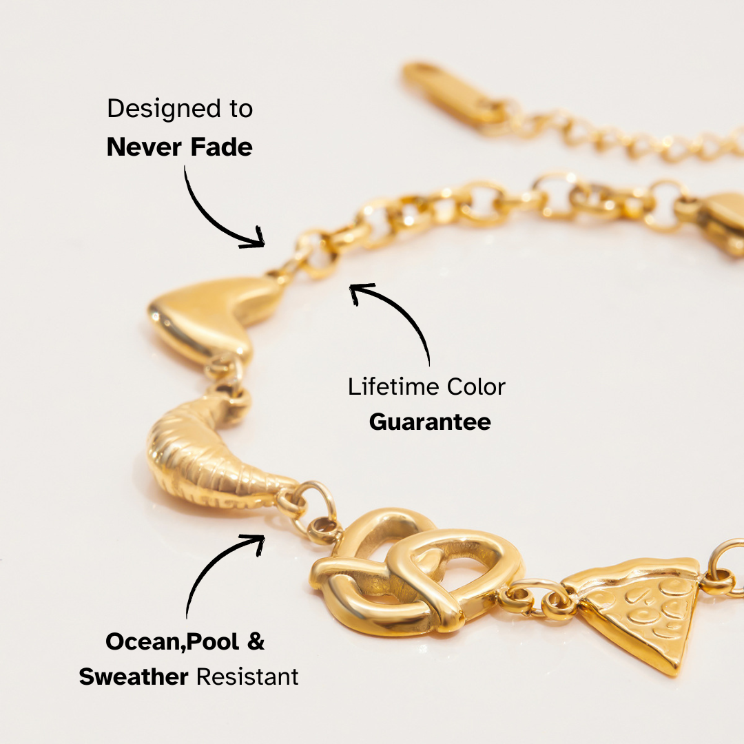 Close-up of pretzel and pizza charms on gold bracelet