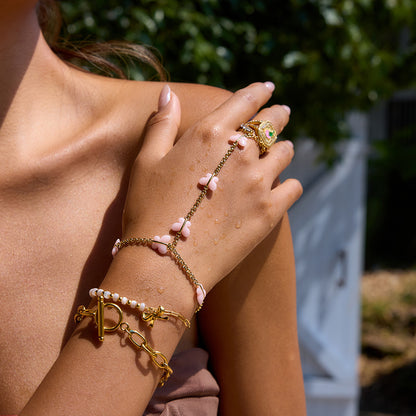Close-up of a hand wearing gold bracelets and rings with a blurred outdoor background