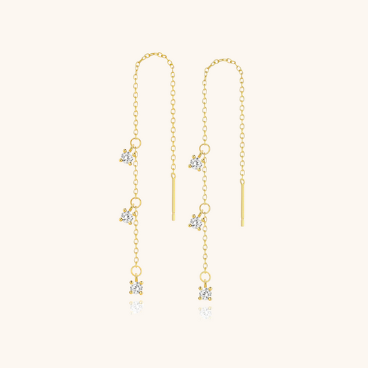 Gold threader earrings with crystal charms displayed on soft cream background