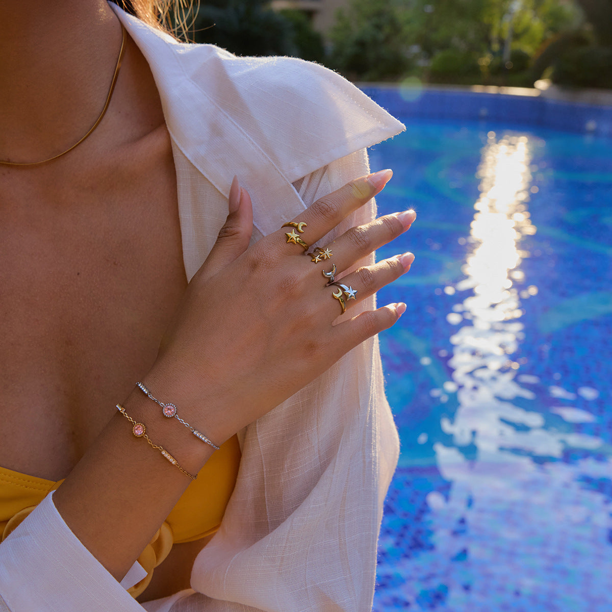 Model wearing adjustable celestial rings by the pool