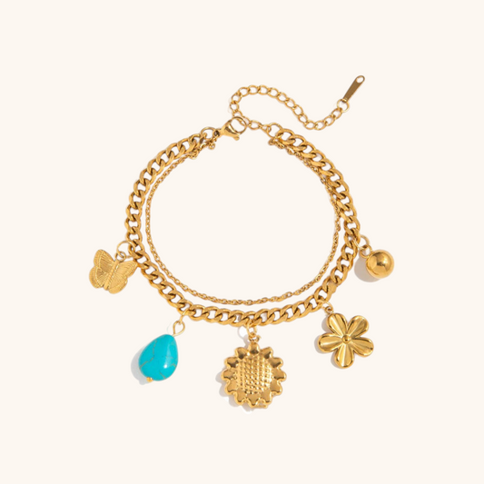 Delicate gold bracelet with flower and butterfly charms styled on a summer outfit