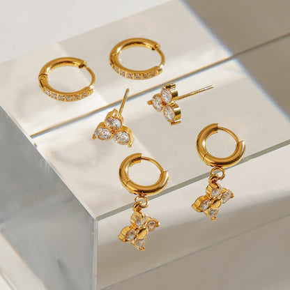 Gold hoop earrings with floral-shaped CZ drop charms, shown in daylight
