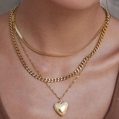 Close-up of a person wearing multiple gold necklaces with heart pendants.