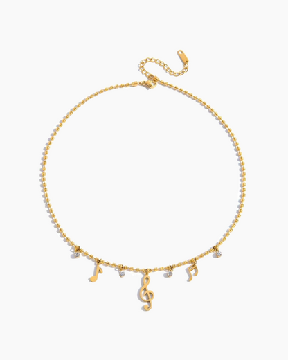 Gold necklace with musical note charms on a white background