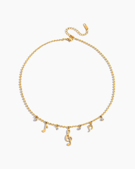 Gold necklace with musical note charms on a white background