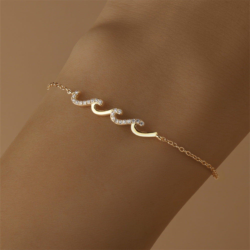 Delicate gold wave bracelet on wrist with sparkling stones