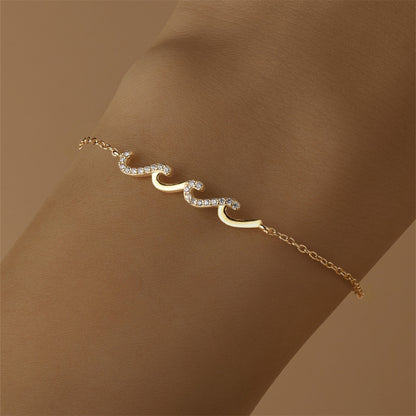 Delicate gold wave bracelet on wrist with sparkling stones