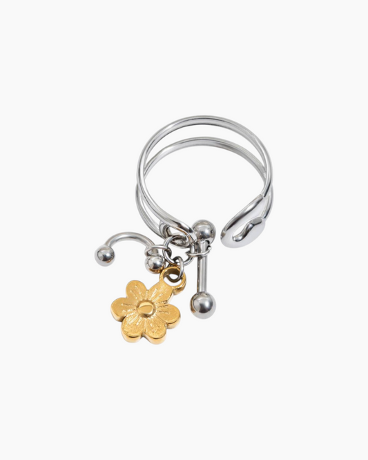 Silver ring with a gold flower charm on a white background