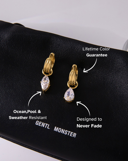 Gold and diamond earrings on a black surface with product features highlighted.
