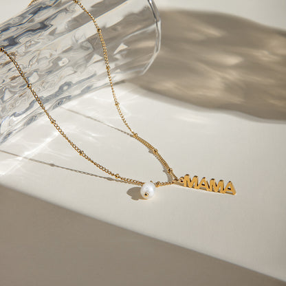 Gold chain necklace with vertical MAMA charm and pearl, styled on a marble background