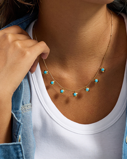 Necklace with turquoise stones worn by a person, close-up view.
