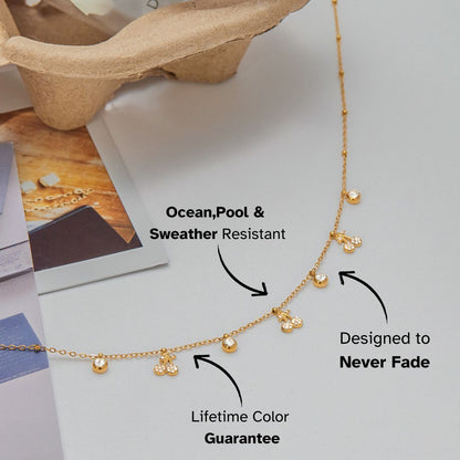 Flat lay of gold necklace with cherry and crystal charms styled on magazine background