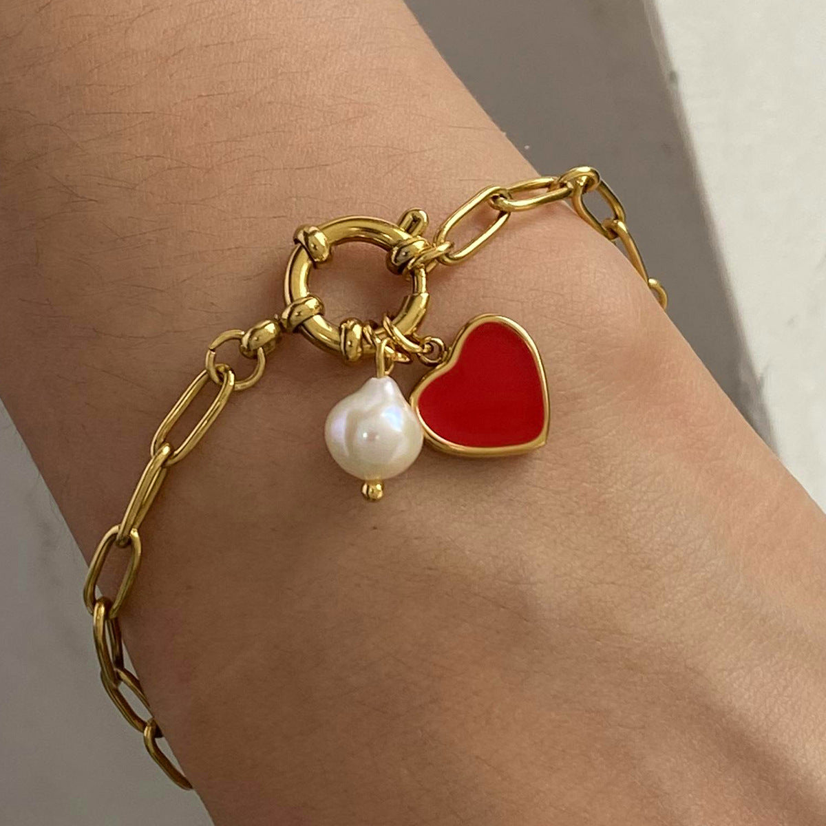 Close-up of gold heart charm bracelet on wrist, styled with minimalist elegance