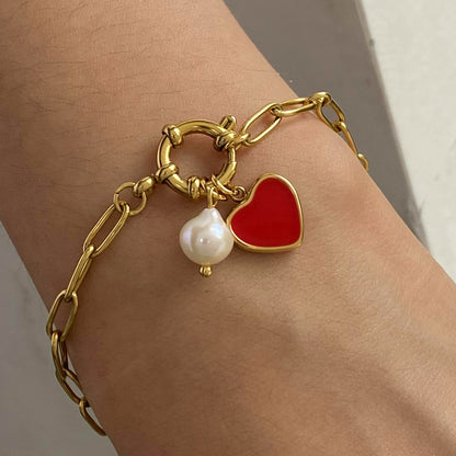 Close-up of gold heart charm bracelet on wrist, styled with minimalist elegance