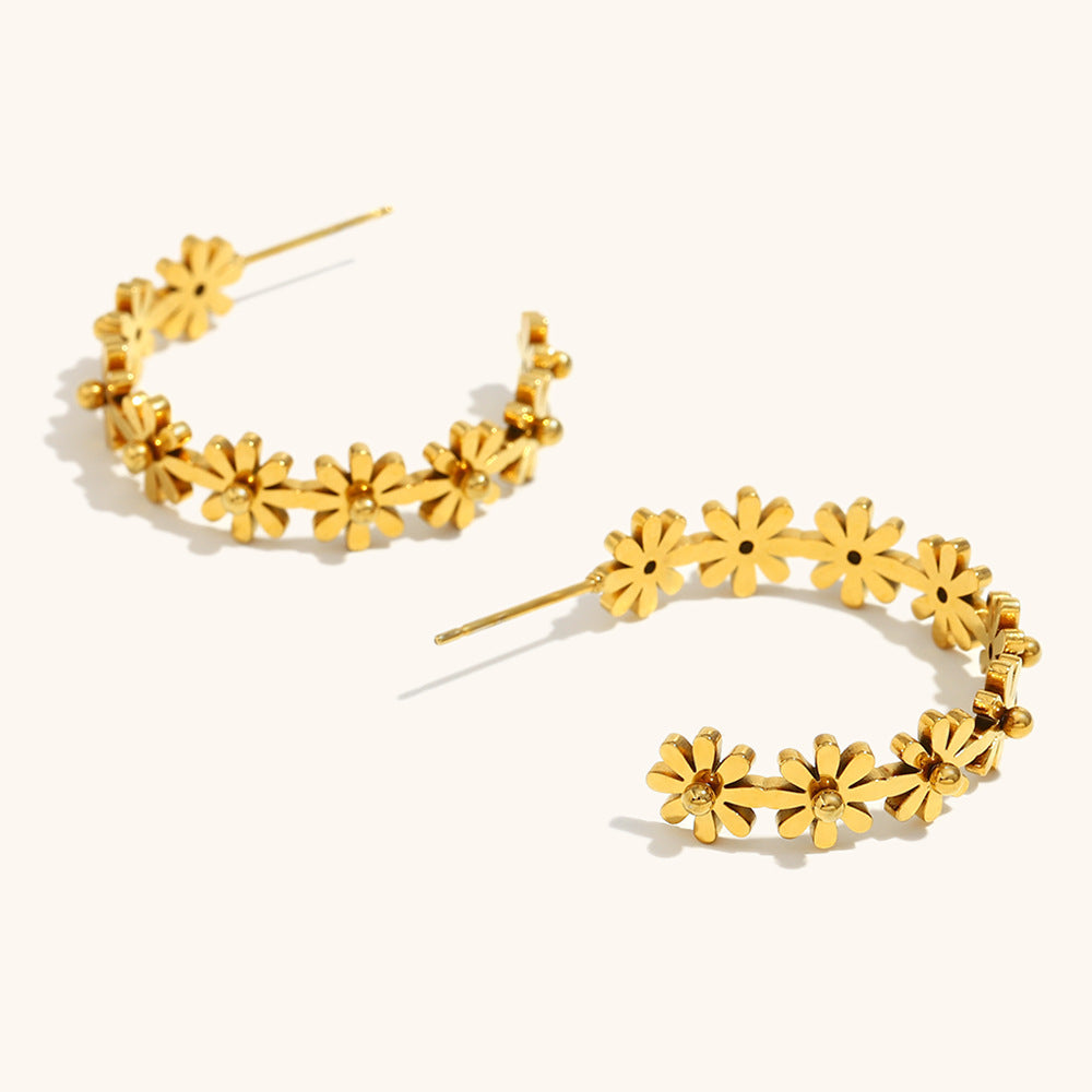 zoomed view of layered daisy hoop earrings with polished gold petals and 3D floral texture