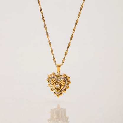 Close-up of double pendant gold necklace featuring vintage heart and crystal bar charms