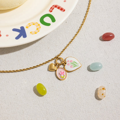 Close-up of dual heart-shaped gold enamel pendants with shell and flower accents
