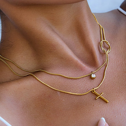 Gold necklace with a cross pendant on a person's neck