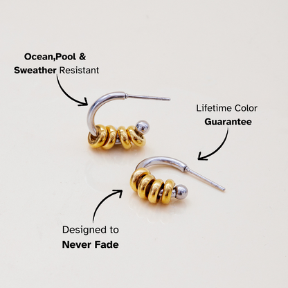 Close-up of mixed metal hoop earrings with stacked golden rings