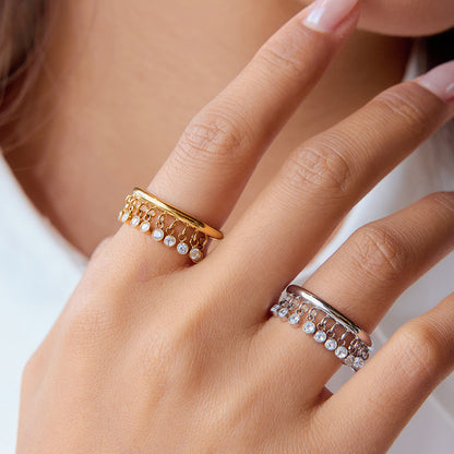 Gold and silver dangle ring worn on model hand with glossy nails