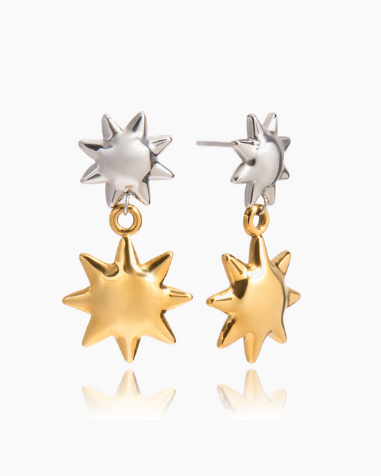 Pair of star-shaped earrings in gold and silver on a white background